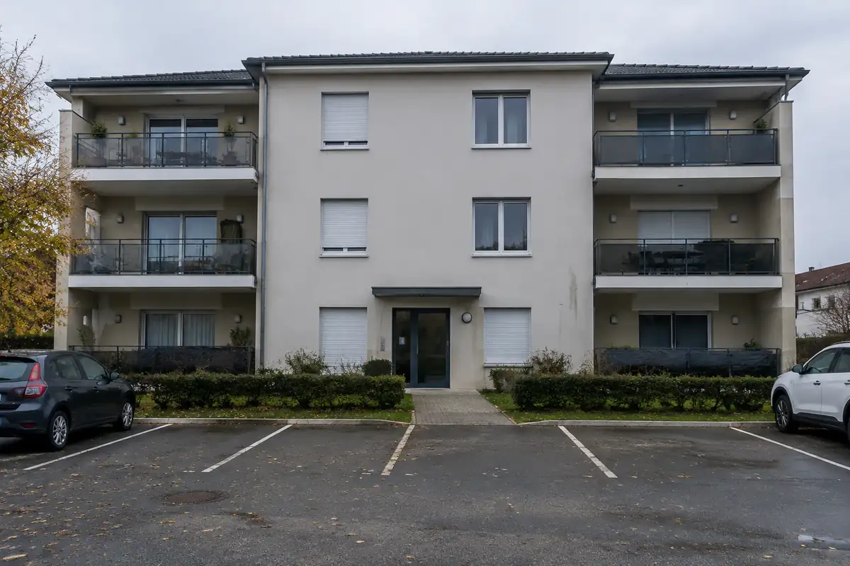 Façade d'un petit immeuble récent avec balcons sous un ciel gris